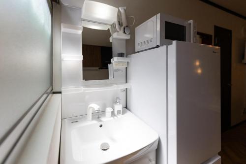 a small kitchen with a sink and a refrigerator at OB 関西空港 大阪梅田 心斎橋直通 京セラドーム1分 usj10分 静かな住宅街 専用駐車場付き in Osaka