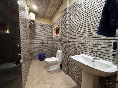 a bathroom with a white toilet and a sink at The Gulmohar Inn in Guwahati