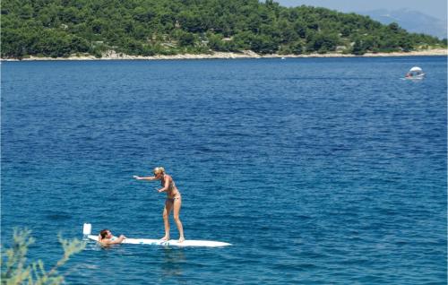 a woman standing on a surfboard in the water at 1 Bedroom Nice Apartment In Necujam in Nečujam