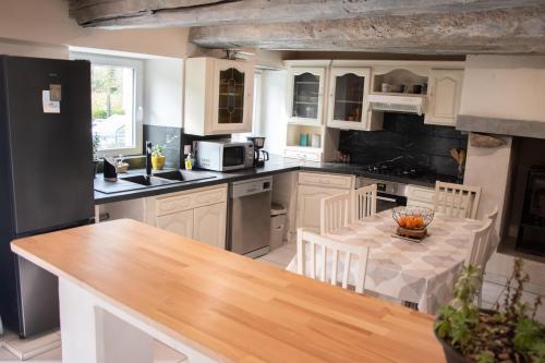 une cuisine avec des armoires blanches et une table en bois dans l'établissement Belle maison familiale dans la campagne Bretonne, à La Croix-Helléan