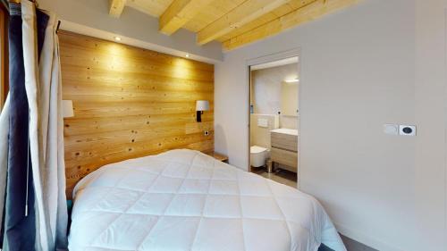 a bedroom with a white bed and a wooden wall at Les Neiges in Saint-Sorlin-dʼArves
