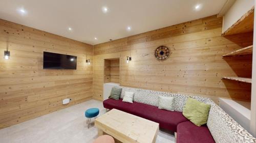 a living room with a couch and a tv at Les Neiges in Saint-Sorlin-dʼArves