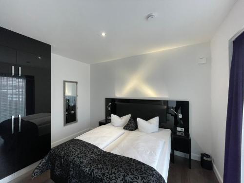 - une chambre avec un grand lit blanc et une tête de lit noire dans l'établissement Lifestyle Apartments, à Villingen-Schwenningen