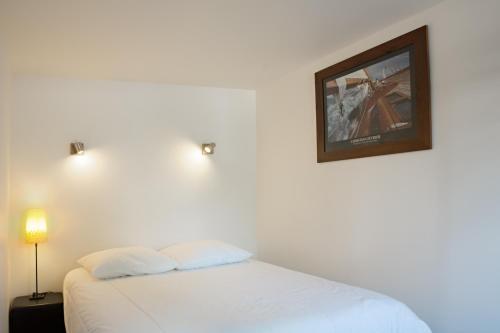 a bedroom with a white bed with a picture on the wall at Le Loft in Honfleur