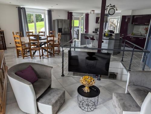 Il comprend un salon doté d'une télévision, de chaises et d'une table. dans l'établissement Gite La grange de Louis SPA et SAUNA, à Araules