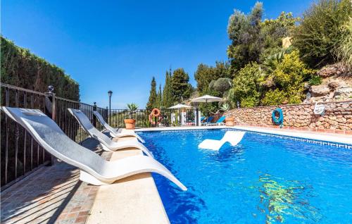 a swimming pool with white lounge chairs next to it at 7 Bedroom Stunning Home In Frigiliana in Acebuchal