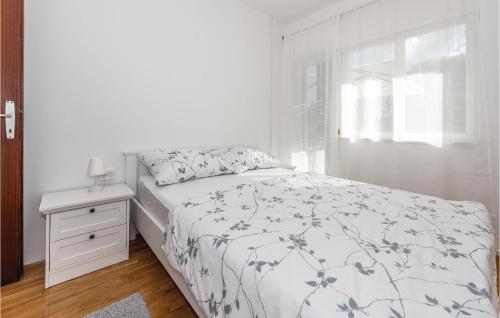 a white bedroom with a bed and a night stand at Three-Bedroom Holiday Home In Unesic in Unešić