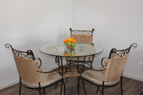 a glass table with four chairs and a bowl of fruit at Greyfriars Motel in Greytown