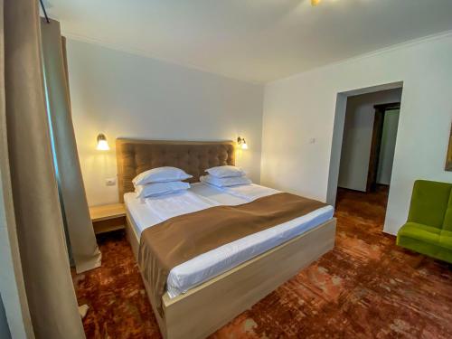 a bedroom with a bed and a green chair at Pension Casa cu Tei in Sărata-Monteoru