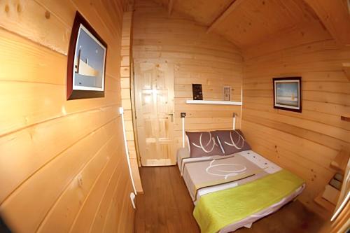 a small room with a bed in a wooden cabin at Bungalow charmant à Vincendo avec piscine partagée in Saint-Joseph