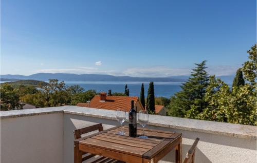 a bottle of wine on a wooden table on a balcony at Gorgeous Apartment In Njivice With Wifi in Njivice
