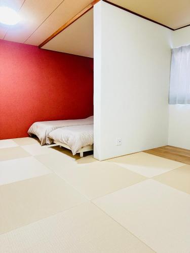 a room with two beds and a red wall at MA House in Osaka
