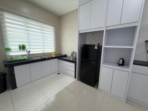 a kitchen with white cabinets and a black refrigerator at 万里望 Menglembu Bestari Homestay in Menglembu