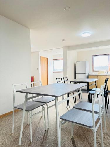 a room with tables and chairs and a refrigerator at MA House in Osaka