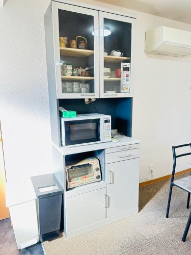 a kitchen with white cabinets and a microwave at MA House in Osaka