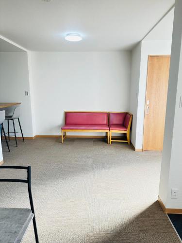 an empty room with a red couch in the corner at MA House in Osaka