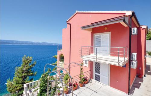 a red building with a balcony overlooking the water at One-Bedroom Apartment In Stanici in Celina