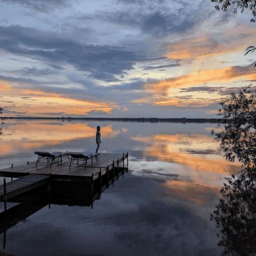 a person standing on a dock in the water at sunset at Comfy Waterfront Suite 2 Double Beds Ensuite in Belleville