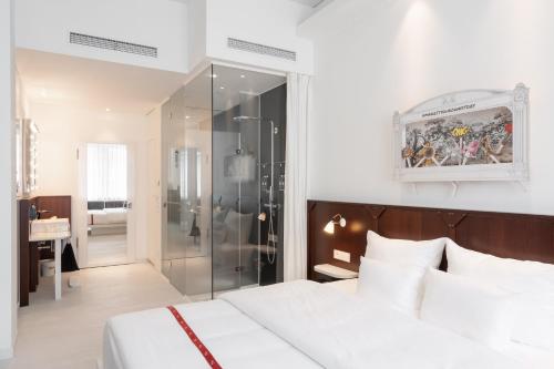 a bedroom with a white bed and a glass shower at Ruby Leni Hotel Dusseldorf in Düsseldorf