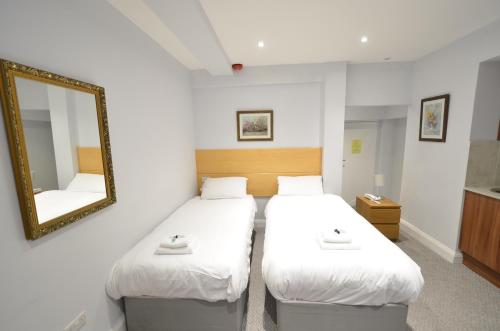 two beds in a room with a mirror at Amber Residence Hotel-Suites in London
