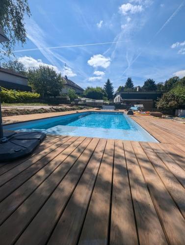 une piscine avec une terrasse en bois et un ciel dans l'établissement Blue House, à Hérimoncourt