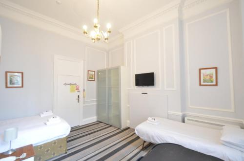 a white room with two beds and a tv at Amber Residence Hotel-Suites in London