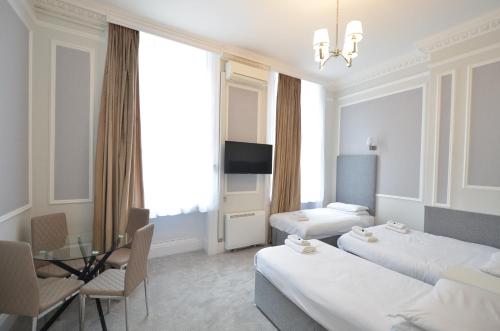 a hotel room with two beds and a table and chairs at Amber Residence Hotel-Suites in London