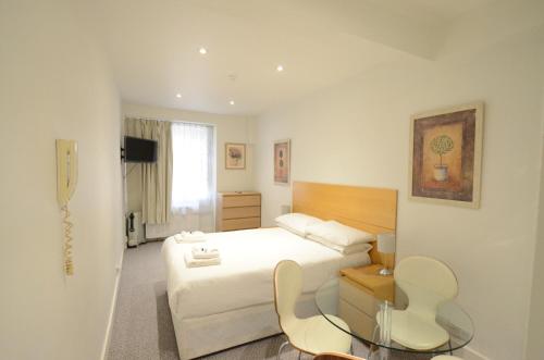 a bedroom with a bed and a table and chairs at Amber Residence Hotel-Suites in London
