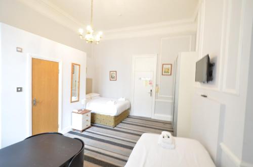 a white room with two beds and a television at Amber Residence Hotel-Suites in London