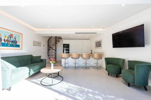 Il comprend un salon doté d'un mobilier vert et d'une télévision à écran plat. dans l'établissement Elegant Duplex with Private Garden Terrace, à Cannes
