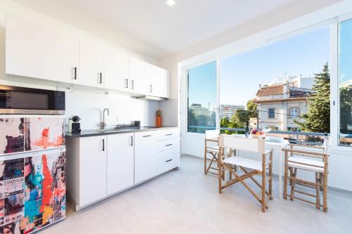 une cuisine avec des placards blancs et une grande fenêtre dans l'établissement 1-Br Apartment Quiet Area near Cannes Center, à Cannes