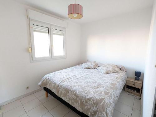 une chambre blanche avec un lit et une fenêtre dans l'établissement Appartement 4 pers. avec piscine, parking, animaux admis - FR-1-387-211, à Marseillan