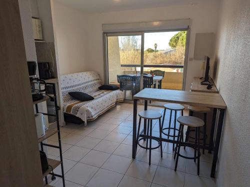 un salon avec une table, des chaises et un canapé dans l'établissement Appartement 4 pers. avec piscine, parking, animaux admis - FR-1-387-211, à Marseillan