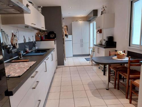 une cuisine avec des armoires blanches et une table à l'intérieur dans l'établissement Villa calme, terrasses, animaux acceptés, parking, WiFi - FR-1-479-202, à Étel