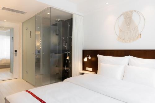 a bedroom with a white bed and a glass shower at Ruby Claire Hotel Geneva in Geneva