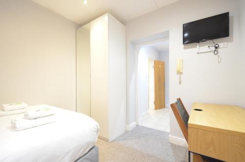 a bedroom with a bed and a tv on the wall at Amber Residence Hotel-Suites in London