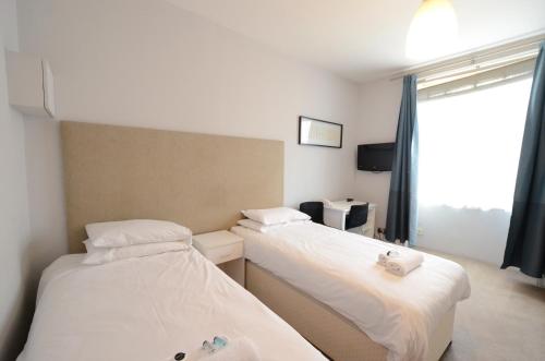 two beds in a room with a window at Amber Residence Hotel-Suites in London