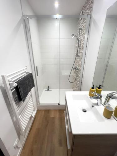 une salle de bain blanche avec une douche et un lavabo dans l'établissement Colours Home Plein coeur de Poitiers, à Poitiers
