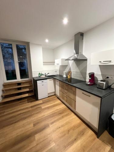 Il comprend une cuisine avec des appareils en noir et blanc et du parquet. dans l'établissement Colours Home Plein coeur de Poitiers, à Poitiers