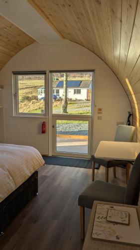 a bedroom with a bed and a table and two windows at Glengoulandie Glamping in White Bridge