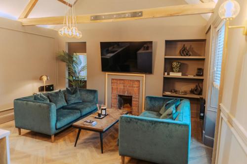 a living room with two blue couches and a fireplace at Magistrates Penthouse Suite - Town Centre Apartments with Spa in Morpeth