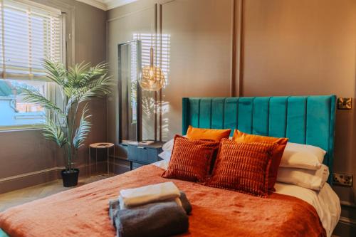 a bedroom with a large bed with orange pillows at Magistrates Penthouse Suite - Town Centre Apartments with Spa in Morpeth
