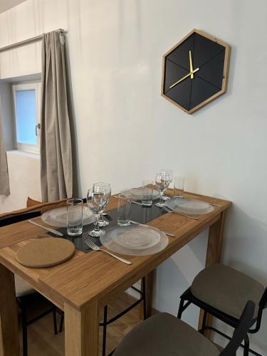une table en bois avec des verres et une horloge au mur dans l'établissement L'escapade du Gros Horloge, à Rouen