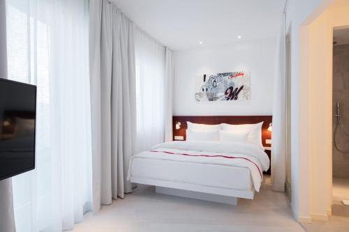 a white bedroom with a bed and a tv at Ruby Marie Hotel Vienna in Vienna