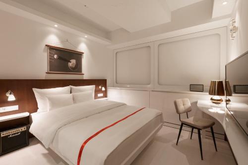 a white bedroom with a large bed and a desk at Ruby Luna Hotel Dusseldorf in Düsseldorf