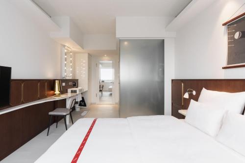 a bedroom with a large bed and a desk and a kitchen at Ruby Luna Hotel Dusseldorf in Düsseldorf