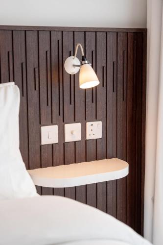a bedroom with a wooden wall with a bed and a lamp at Ruby Zoe Hotel London in London