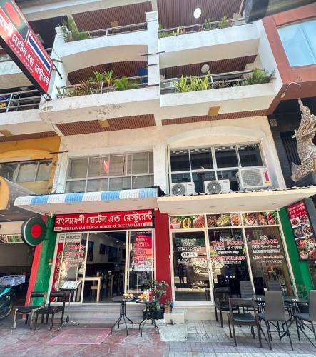 a restaurant with tables and chairs in front of a building at Noorjahan Guesthouse Pattaya in Pattaya
