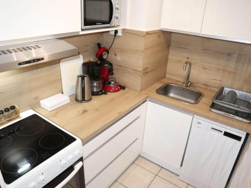 une petite cuisine avec une cuisinière et un micro-ondes dans l'établissement Bel appart 2P, rénové, balcon expo sud, Les Orres - FR-1-322-199, aux Orres