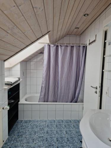 a bathroom with a purple shower curtain and a tub at FeWo Stauber in Amtzell